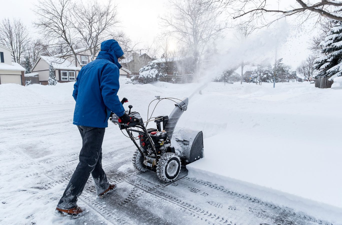 A BE&P Services professional clearing snow from a residential driveway in West Springs, AB, ensuring safety and accessibility.